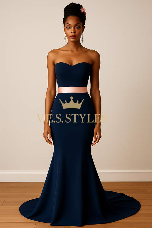 Woman wearing a navy strapless gown with a pink belt on a plain background, featuring the brand– V.E.S. Styles